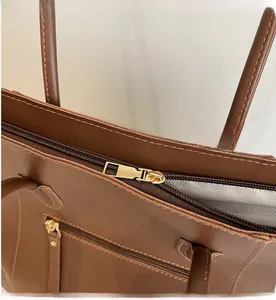 Detailed close-up of smooth metal zipper and striped lining on brown tote bag