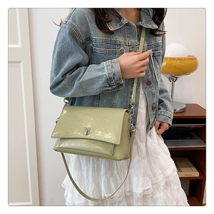 Detail der pistaziengrünen Lackleder-Schultertasche mit silberner Schnalle am Model