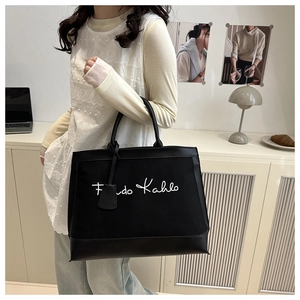 Detail of black tote bag featuring Frida Kahlo script and stylish shoulder strap