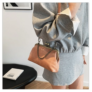 Detail of light beige crocodile pattern handbag featuring a vintage metal frame and clasp