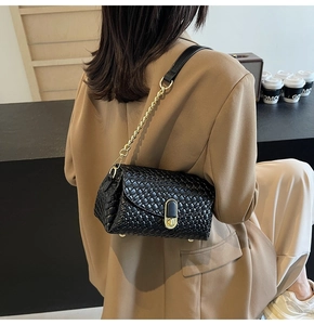 Gros plan du sac en cuir tressé noir avec bandoulière chaîne dorée porté par un mannequin