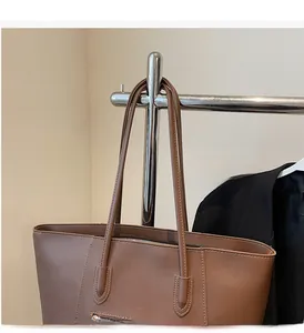 Close-up of brown PU leather tote bag featuring durable handles and functional outer zipper