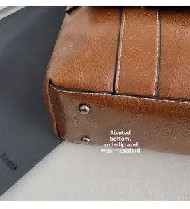 Dettaglio del fondo della borsa marrone vintage con rivetti e cuciture bianche