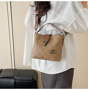 Detail of printed bucket bag featuring monogram pattern and metallic kangaroo logo buckle