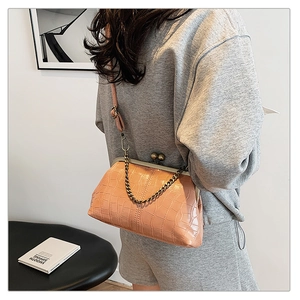 Model wearing a stone pattern salmon crossbody bag with chain handle and vintage metal clasp