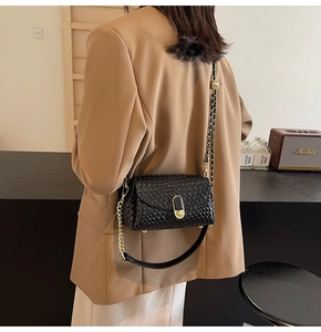 Détail d'un sac bandoulière tressé noir avec fermoir rotatif doré et double bandoulière