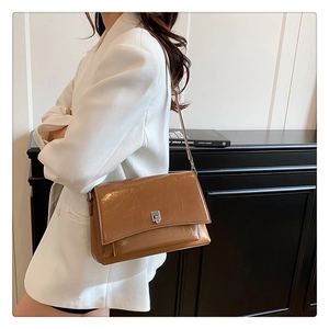 Braune Vintage-Schultertasche aus Öl-Wachs-Leder mit silberner Schnalle am weißen Blazer