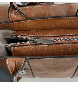 Dettaglio zip in metallo e cuciture bianche su borsa marrone con trama a coccodrillo