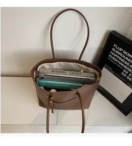 Detailed interior of large brown leather tote bag showing laptop and spacious compartments