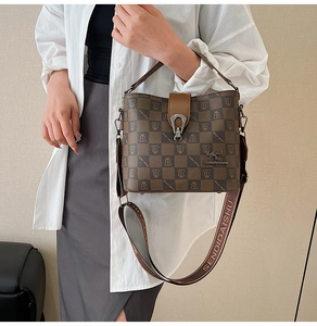 Detailed view of the checkered bucket bag with wide logo strap worn by a model
