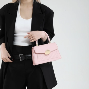 Sac à main rose avec boucle galet et texture crocodile porté par un mannequin