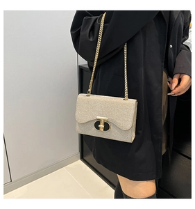 Sac bandoulière pailleté doré champagne avec chaîne porté par un mannequin en manteau