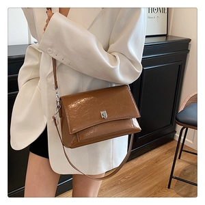 Nahaufnahme braune Ölwachs-Ledertasche mit silberner Schnalle auf weißem Blazer