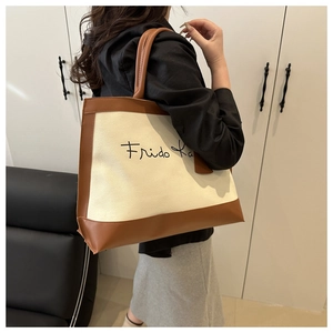 Canvas tote bag with Frida Ka print and brown leather trim shown on model shoulder