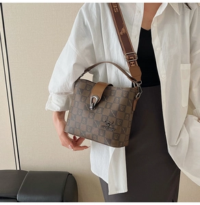 Detail of a brown checkered bucket bag featuring metal kangaroo logo and canvas strap