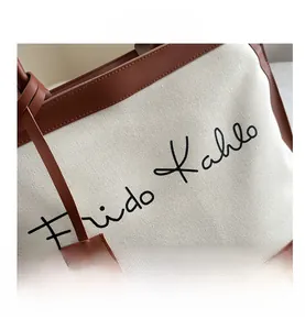Detail of canvas tote bag with brown leather trim and Frida Kahlo calligraphy