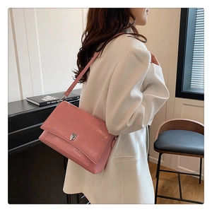 Detail einer glänzenden rosa Achseltasche aus Leder mit silberner Schnalle am Model