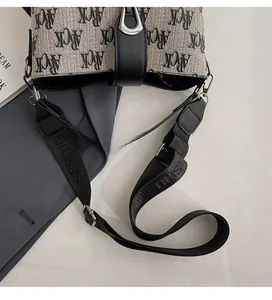Detail of adjustable woven shoulder strap and printed canvas bucket bag surface