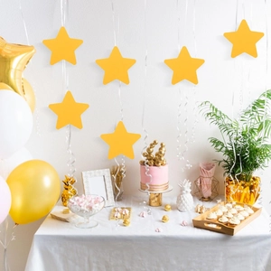 Stelle di carta gialle appese sopra un tavolo da festa con torte e decorazioni