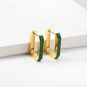 Close-up of gold rectangular earrings with emerald green zircon stones on stone stand