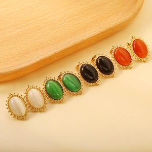Macro detail of oval stud earrings with white cat eye stones and gold beaded edges