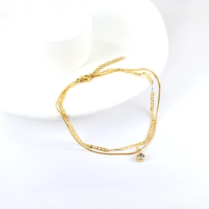 Detail view of double-layer gold anklet with hollow butterfly design and crystal charm