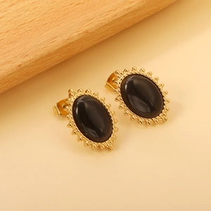 Macro detail of vintage oval earrings featuring black stone and golden beaded edge