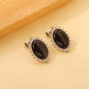 Macro detail of vintage oval stud earrings featuring black cat eye stone and beaded trim