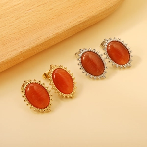 Detail of oval earrings with vintage beaded edges and orange-red cat eye stones