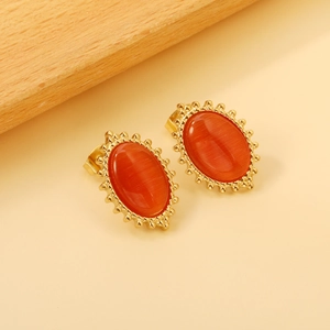 Detailed view of vintage gold earrings with oval orange cat eye stones on a wooden background