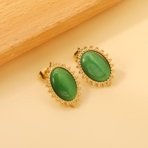 Detail view of vintage gold stud earrings featuring oval green cat-eye stones with beaded edges