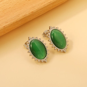 Detailed close-up of oval white cat eye stone earrings with decorative milgrain silver edges