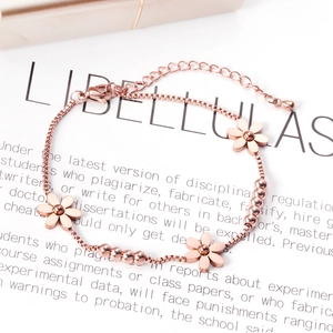 Dettaglio del bracciale in oro rosa con ciondoli floreali e chiusura a moschettone