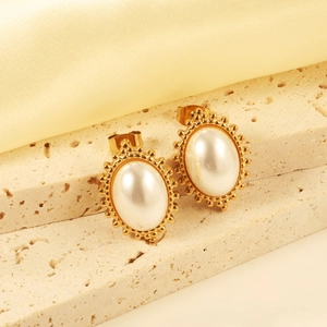 Detailed view of vintage gold stud earrings with oval white cat eye stones on a stone base