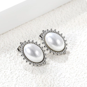 Close-up of vintage oval white cat-eye stone earrings with silver beaded border details