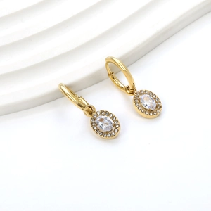 Close-up of gold hoop earrings with oval crystal drop and sparkling pavé details