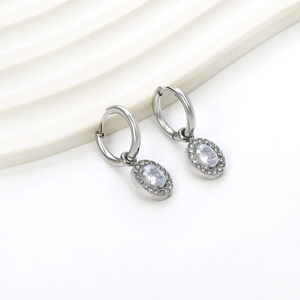 Detail view of silver oval zircon drop hoop earrings on a minimalist white background
