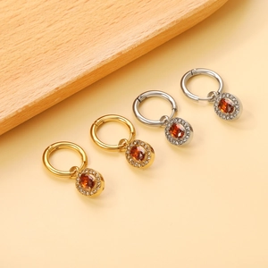 Detail of gold and silver hoop earrings with amber oval stones and zircon accents