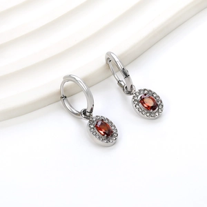 Detailed macro view of silver hoop earrings with oval red gemstones and zircon halo