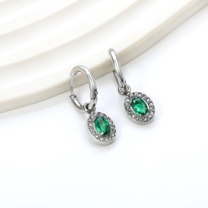 Detailed macro of silver hoop earrings with oval emerald stone and white crystal halo