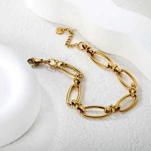 Minimalist gold link chain bracelet with lobster clasp and round charm on white stone