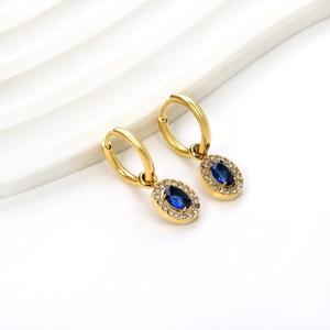 Detailed shot of gold hoop earrings with oval blue sapphire and zircon accents