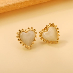 Détail de boucles d'oreilles cœur avec pierre œil de chat et bordure dorée perlée vintage