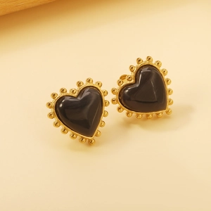 Vue macro de boucles d'oreilles cœur vintage avec pierre œil de chat noire et bord perlé