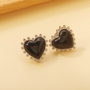 Gros plan de boucles d'oreilles cœur vintage avec pierres noires et bords perlés