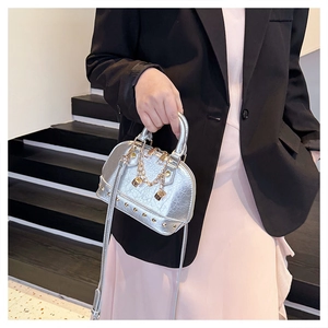 Silver shell bag with gold studs and chain handle details shown by a model