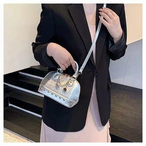 Detail of silver shell bag with gold studs and chain strap shown on model's shoulder