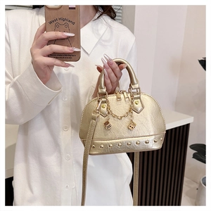 Detail of a golden shell bag featuring metallic pleated texture and gold rivet studs