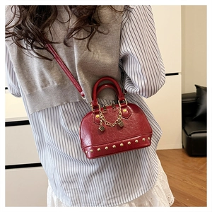 Detailed view of a red shell bag with gold studs and chain strap on a model