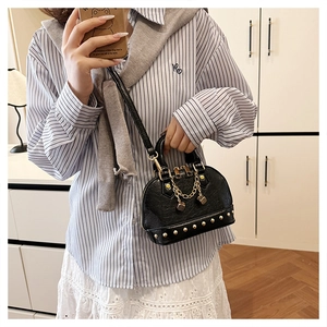 Close-up of black textured dome bag featuring gold rivets and elegant chain pendant